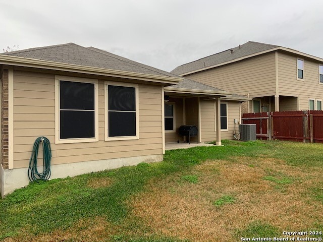 back of property featuring central AC and a lawn