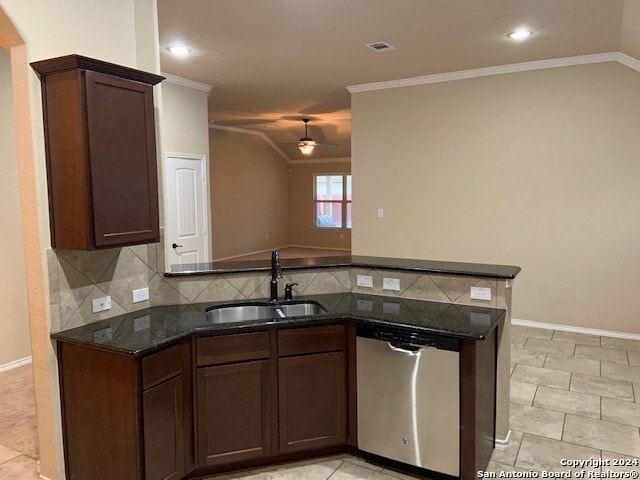 kitchen featuring lofted ceiling, sink, dishwasher, dark stone countertops, and backsplash