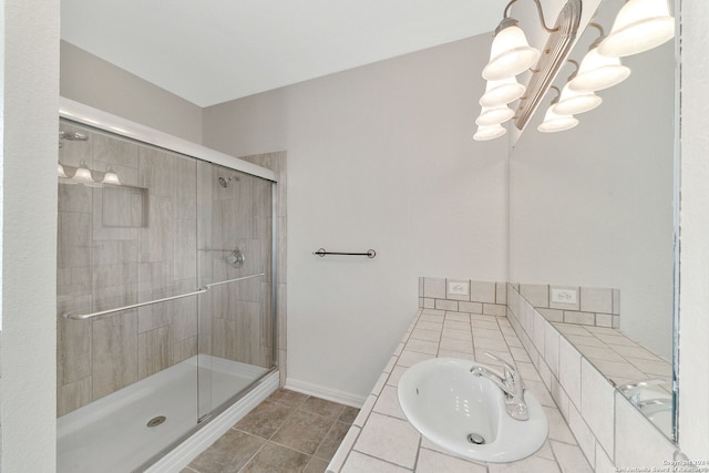 bathroom with a notable chandelier, sink, tile patterned floors, and walk in shower