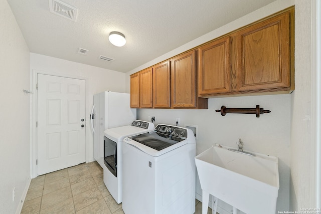 clothes washing area featuring cabinets, sink, separate washer and dryer, and a textured ceiling