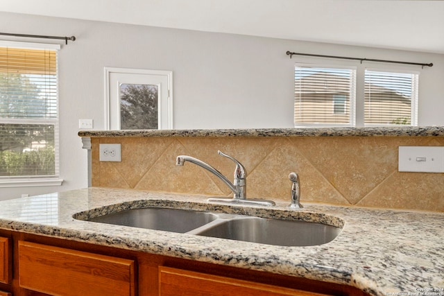 kitchen with sink, a healthy amount of sunlight, decorative backsplash, and light stone countertops