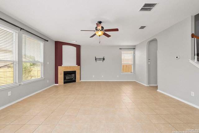 unfurnished living room featuring a fireplace, ceiling fan, and light tile patterned floors