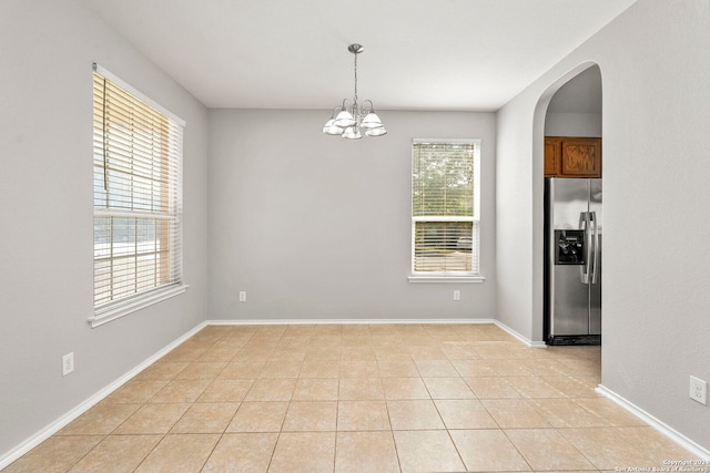 unfurnished dining area featuring light tile patterned floors, plenty of natural light, and a chandelier