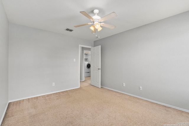 carpeted spare room featuring washer / dryer and ceiling fan