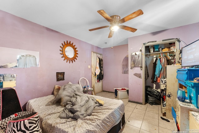 tiled bedroom featuring ceiling fan and a closet