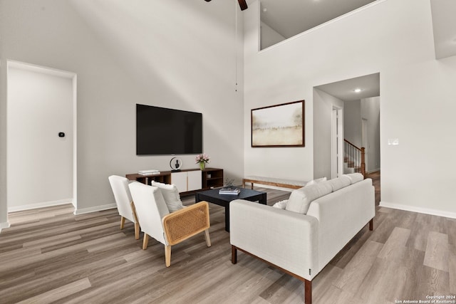 living room with ceiling fan, high vaulted ceiling, and light wood-type flooring