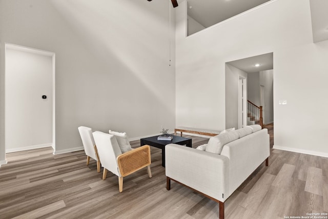 living room featuring light hardwood / wood-style floors, high vaulted ceiling, and ceiling fan