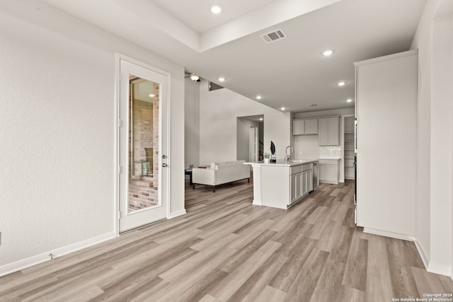 kitchen with a center island with sink, sink, and light hardwood / wood-style flooring