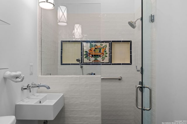 bathroom with toilet, a shower with shower door, and sink