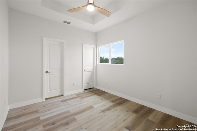 unfurnished bedroom with a raised ceiling, light hardwood / wood-style flooring, and ceiling fan