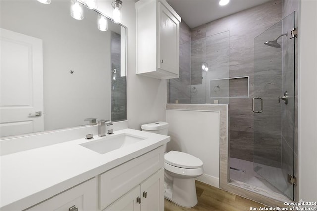 bathroom featuring hardwood / wood-style flooring, toilet, an enclosed shower, and vanity