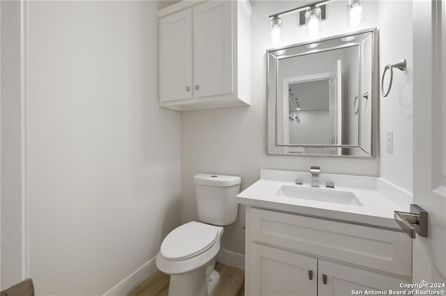 bathroom with hardwood / wood-style flooring, vanity, and toilet