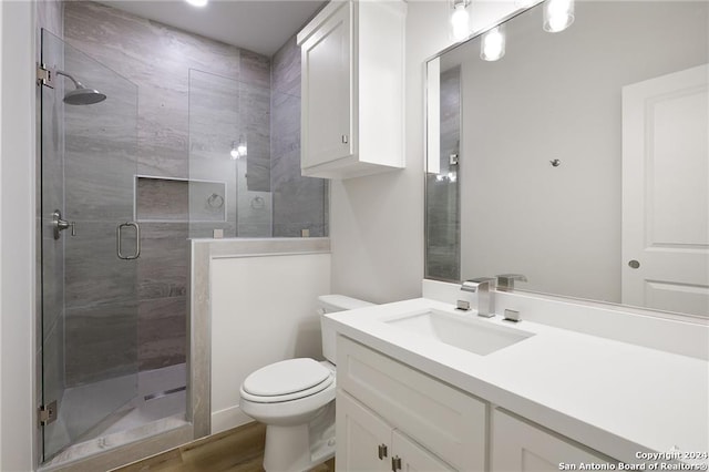 bathroom featuring toilet, vanity, an enclosed shower, and hardwood / wood-style flooring
