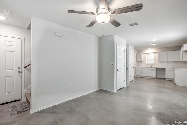 unfurnished living room featuring ceiling fan and sink