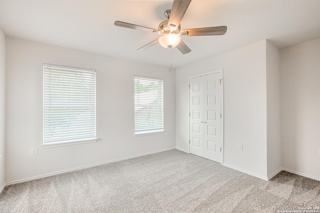 unfurnished bedroom featuring ceiling fan, light colored carpet, and a closet