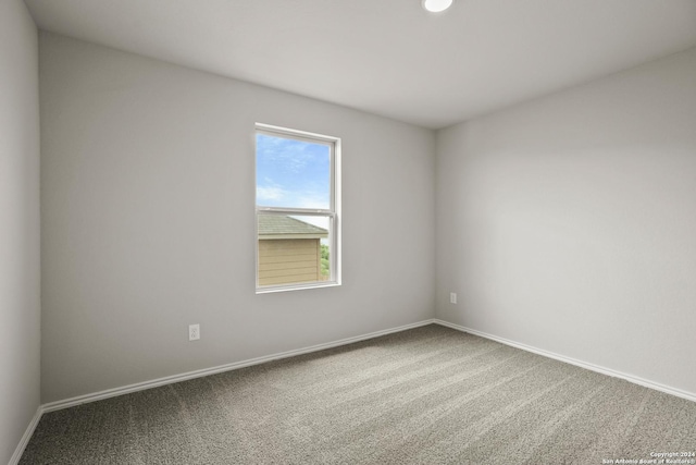 carpeted empty room featuring baseboards