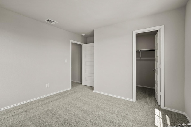 unfurnished bedroom featuring carpet floors, a closet, visible vents, a spacious closet, and baseboards