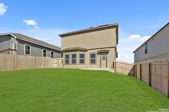 back of house with a lawn and a fenced backyard