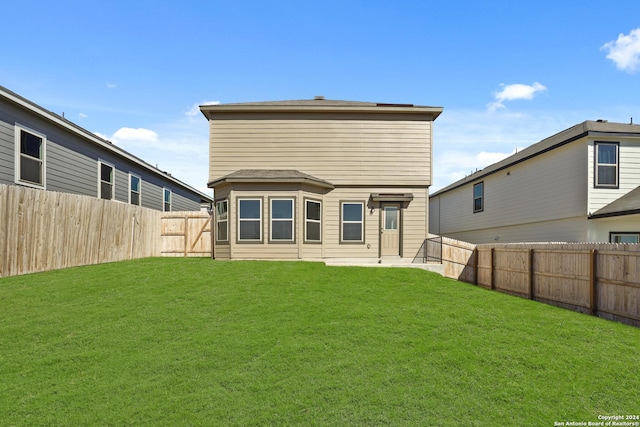 back of house with a fenced backyard and a lawn