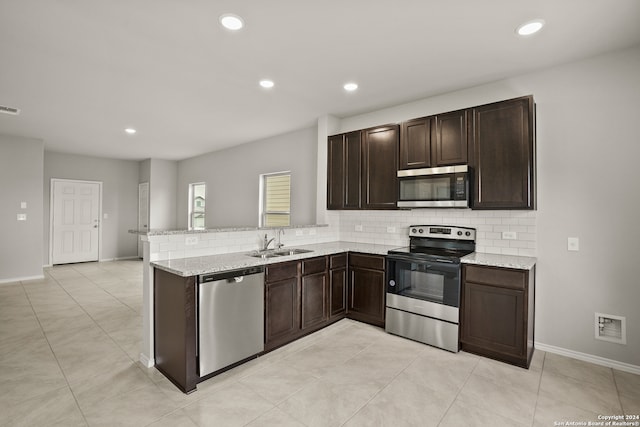 kitchen featuring kitchen peninsula, appliances with stainless steel finishes, tasteful backsplash, light stone counters, and sink