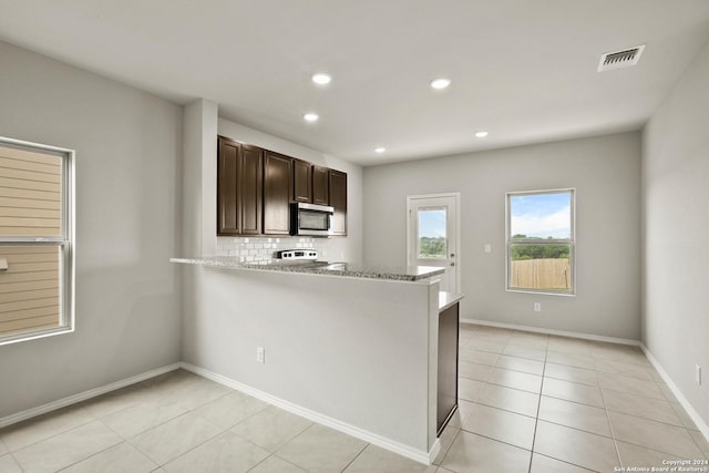 kitchen with visible vents, decorative backsplash, range, stainless steel microwave, and dark brown cabinets