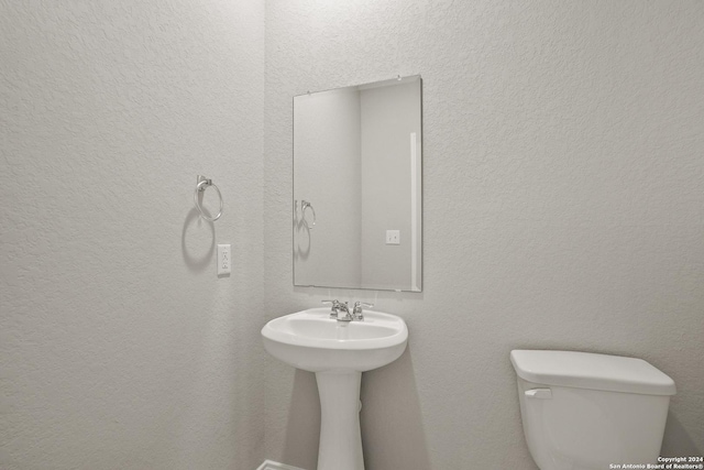 bathroom with a textured wall and toilet