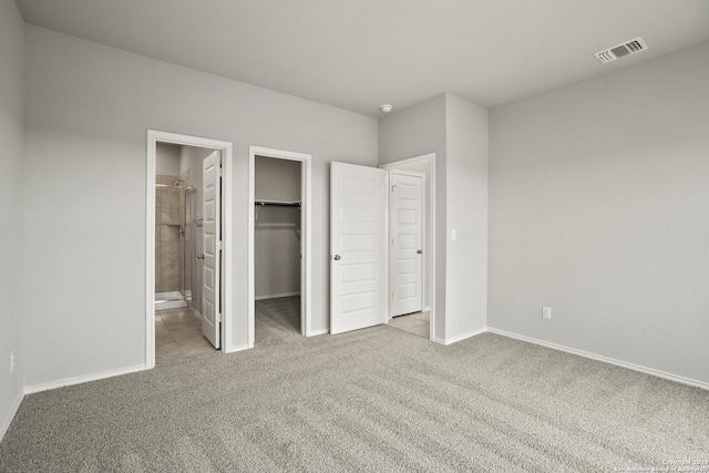 unfurnished bedroom with carpet, visible vents, a spacious closet, and ensuite bathroom