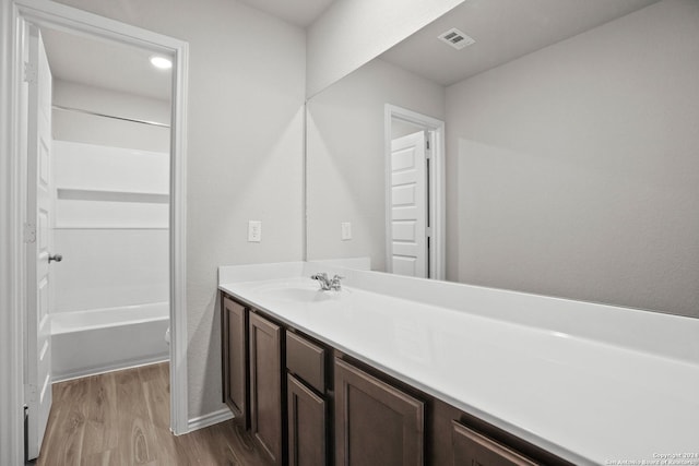 bathroom with visible vents, vanity,  shower combination, and wood finished floors