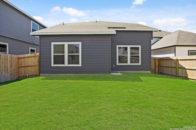 rear view of house with a fenced backyard and a yard