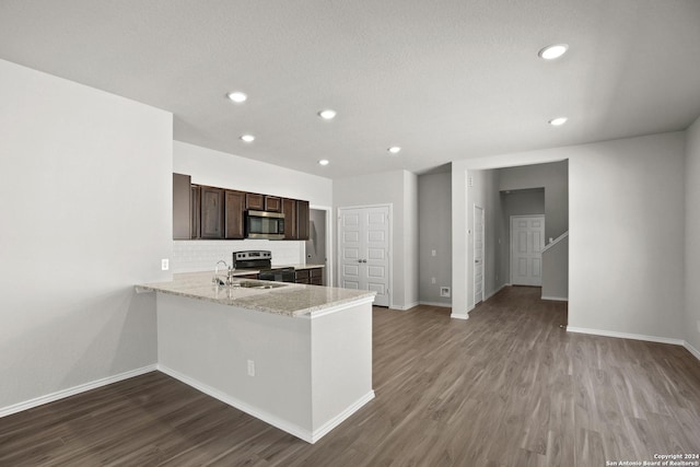 kitchen featuring tasteful backsplash, stainless steel microwave, dark brown cabinets, dark wood finished floors, and electric range