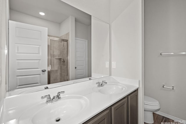 bathroom featuring toilet, a stall shower, double vanity, and a sink