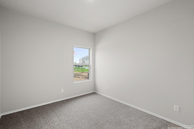 carpeted empty room featuring baseboards