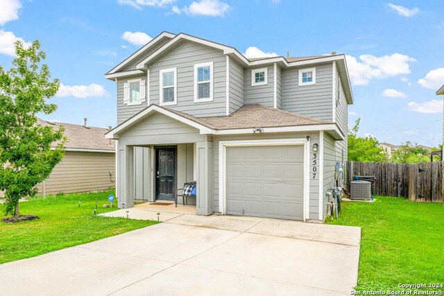 view of property featuring a garage, central air condition unit, and a front lawn