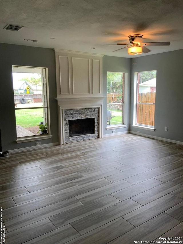 unfurnished living room featuring wood-type flooring, a fireplace, and ceiling fan