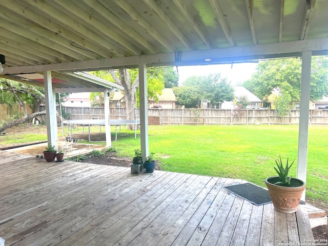 wooden terrace featuring a lawn and a trampoline