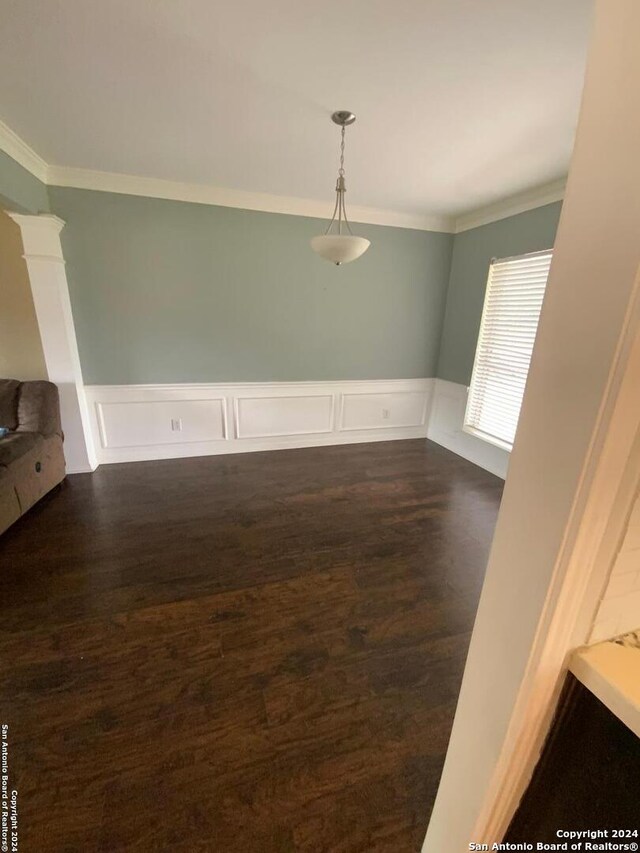 unfurnished room featuring decorative columns, dark wood-type flooring, and crown molding