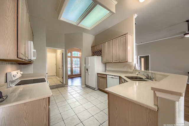 kitchen featuring kitchen peninsula, sink, white appliances, light brown cabinets, and light tile patterned floors