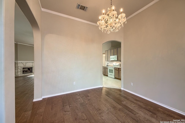 empty room featuring a fireplace, crown molding, a chandelier, and light hardwood / wood-style floors