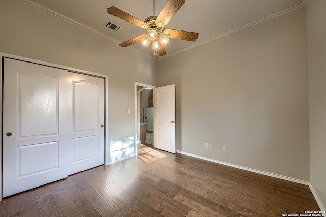 unfurnished bedroom featuring ceiling fan, a closet, crown molding, and hardwood / wood-style flooring