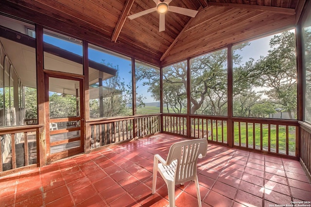 unfurnished sunroom featuring ceiling fan, wood ceiling, a healthy amount of sunlight, and lofted ceiling with beams