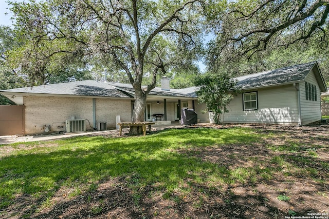 rear view of property featuring a lawn, cooling unit, and a patio