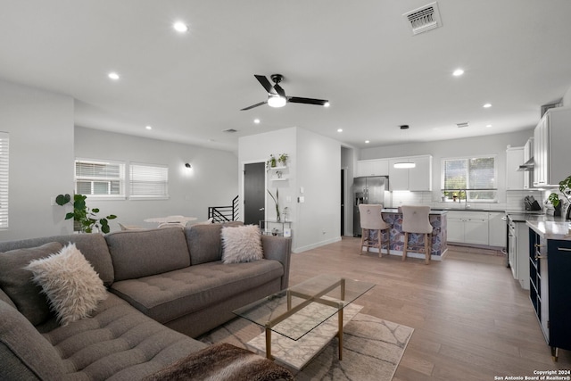 living room with sink, ceiling fan, and light hardwood / wood-style floors