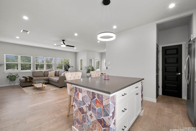 kitchen featuring white cabinetry, ceiling fan, light hardwood / wood-style flooring, stainless steel refrigerator, and pendant lighting