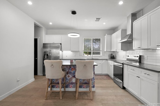 kitchen featuring hanging light fixtures, a breakfast bar, a kitchen island, white cabinetry, and appliances with stainless steel finishes