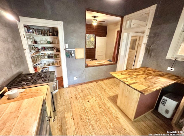 kitchen with butcher block countertops, range with gas stovetop, light wood-type flooring, and ceiling fan