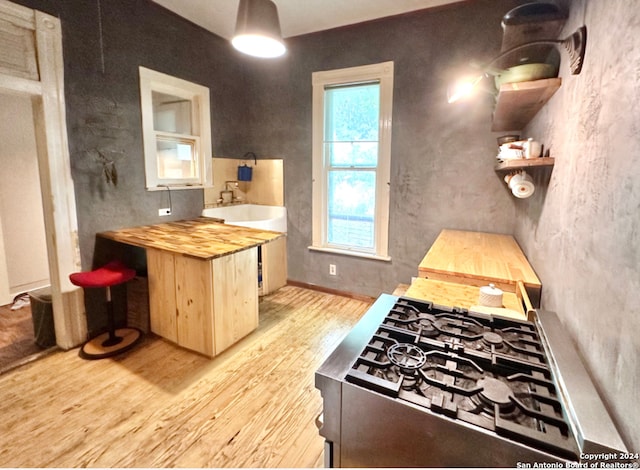 kitchen featuring sink, butcher block countertops, light wood-type flooring, and gas stovetop