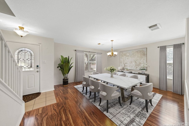 dining area with baseboards, visible vents, dark wood-style flooring, a textured ceiling, and a chandelier