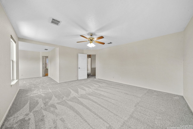 spare room featuring light colored carpet, visible vents, ceiling fan, and baseboards