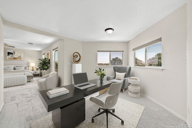 office area featuring light carpet, baseboards, and a textured ceiling