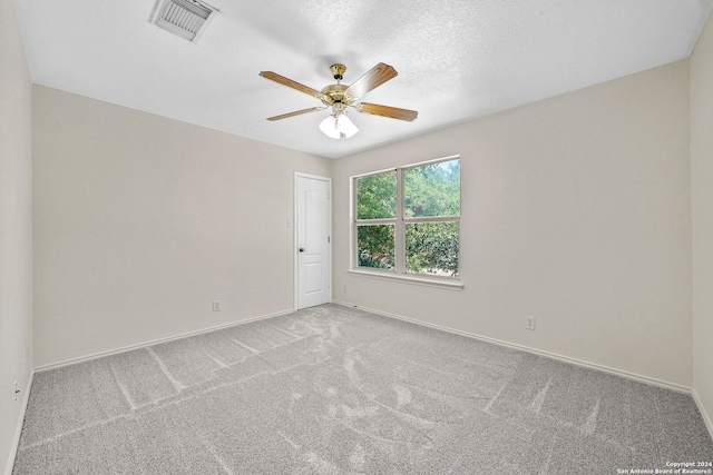 empty room featuring carpet, visible vents, a ceiling fan, a textured ceiling, and baseboards